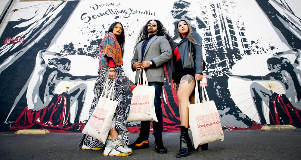 Woman, Man, and Woman standing with tote bags