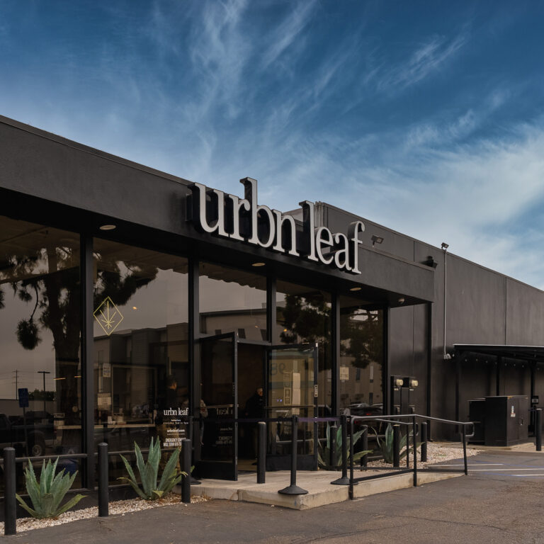 DSC03676-Editjpg - Harborside Exterior view of the Urbn Leaf storefront with large windows, black facade, clear sky, and desert plants near the entrance. DSC03676-Editjpg