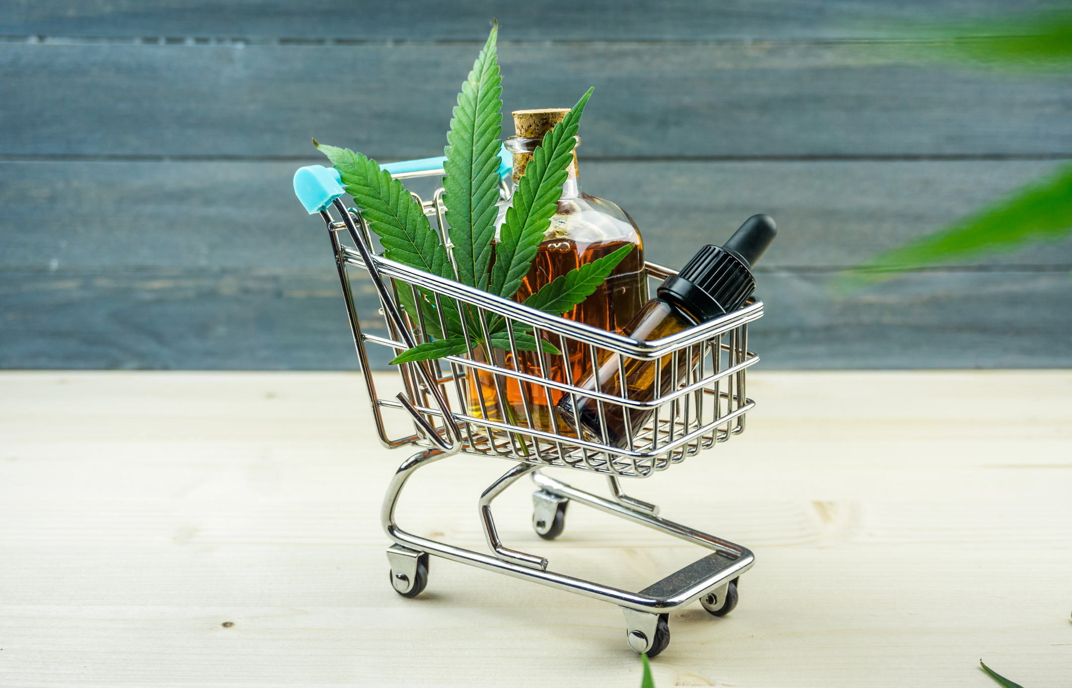 Supermarket trolley with marijuana leafs and medical cannabis oil cbd on wooden backdrop - Harborside Supermarket trolley with marijuana leafs and medical cannabis oil cbd on wooden backdrop Supermarket trolley with marijuana leafs and medical cannabis oil cbd on wooden backdrop